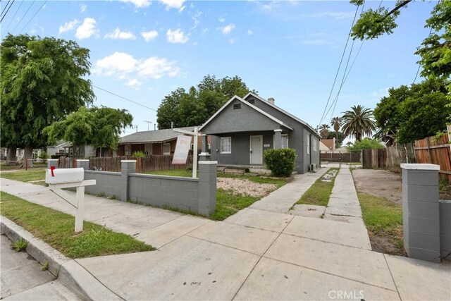 bungalow with a fenced front yard and stucco siding
