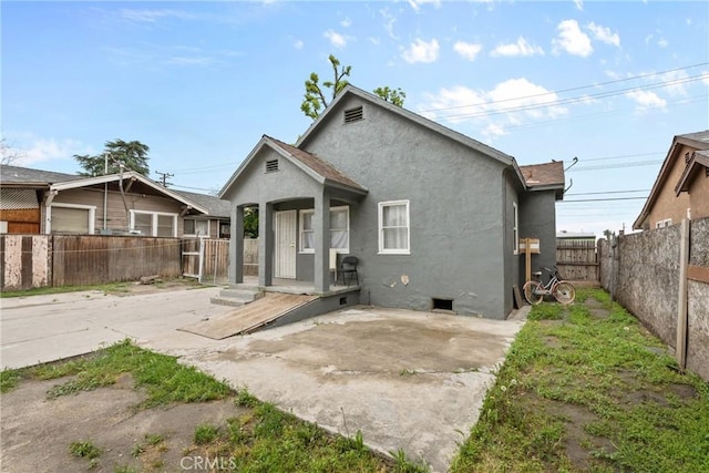 rear view of house featuring stucco siding, a fenced backyard, a patio, and crawl space