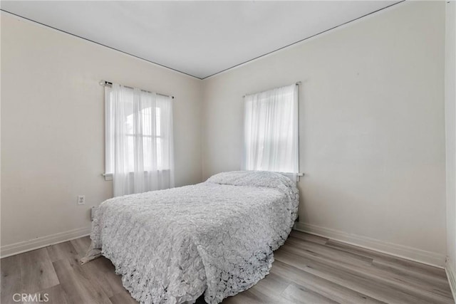 bedroom with light wood-type flooring and baseboards