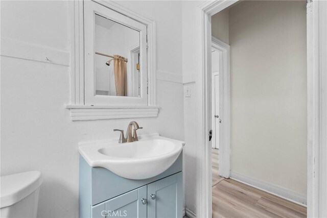 bathroom featuring vanity, wood finished floors, toilet, and baseboards