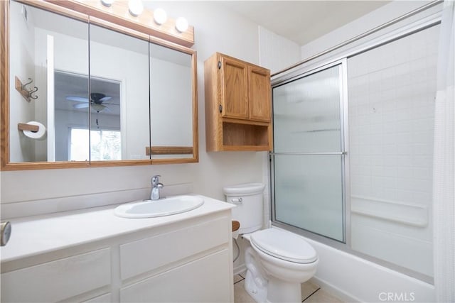 bathroom with toilet, vanity, shower / bath combination with glass door, and a ceiling fan