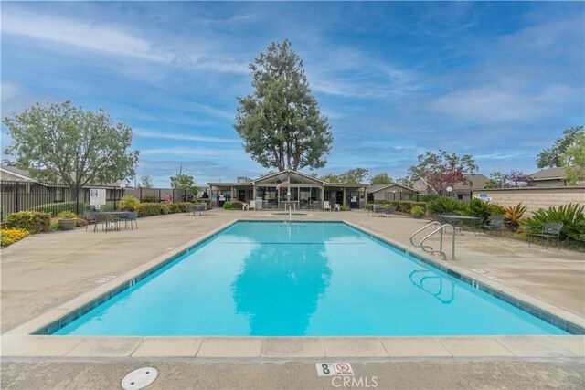 community pool with a patio area and fence