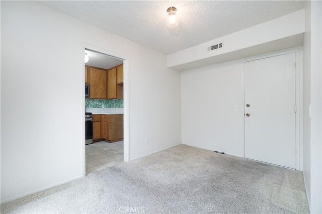 unfurnished room featuring light carpet and a textured ceiling