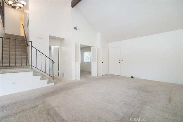 unfurnished living room with high vaulted ceiling, carpet flooring, stairway, beamed ceiling, and a chandelier