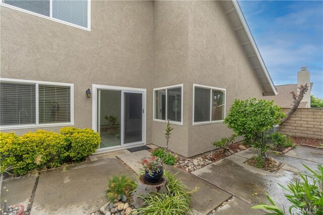 rear view of property featuring a patio area, stucco siding, and fence