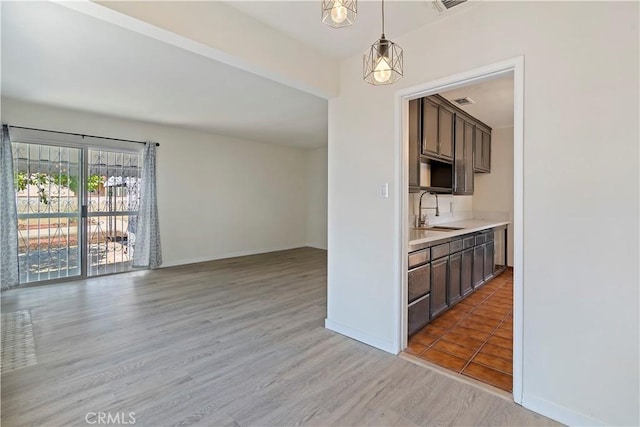 6255 Satsuma Ave, North Hollywood, CA 91606 - kitchen featuring a sink, light countertops, pendant lighting, light wood-type flooring, and dark brown cabinetry