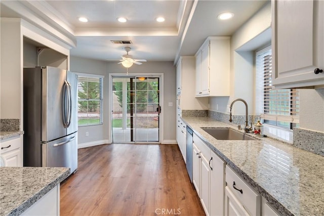 kitchen with appliances with stainless steel finishes, a sink, a raised ceiling, ceiling fan, and white cabinetry