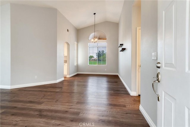 foyer entrance featuring a chandelier, lofted ceiling, dark wood-style flooring, arched walkways, and baseboards
