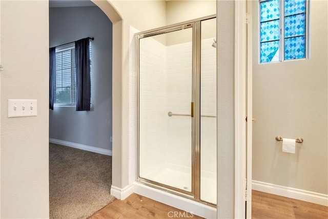 full bath with a shower stall, baseboards, and plenty of natural light