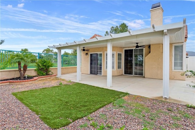 back of house with a ceiling fan, a chimney, a patio, and stucco siding