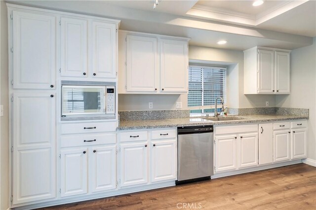 kitchen featuring stainless steel dishwasher, a sink, white microwave, white cabinetry, and light wood-style flooring