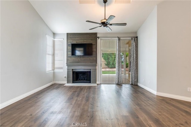 unfurnished living room with a ceiling fan, baseboards, a large fireplace, and wood finished floors