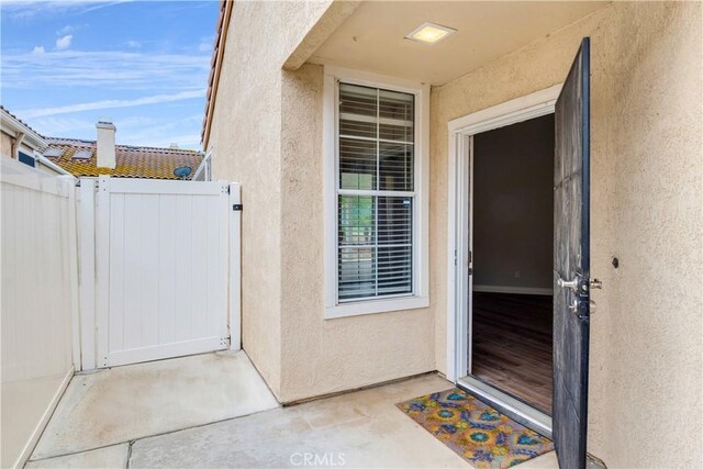 doorway to property with stucco siding and fence