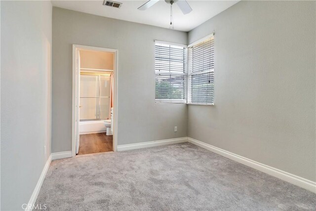 unfurnished bedroom with carpet, baseboards, ensuite bathroom, and a ceiling fan