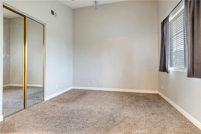 unfurnished bedroom featuring carpet flooring, baseboards, and a closet