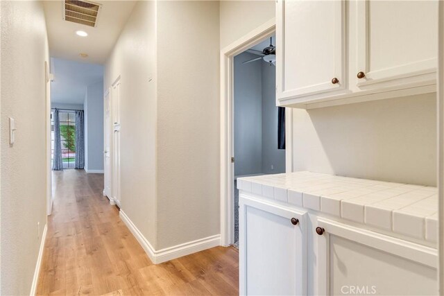 corridor with light wood-style flooring, baseboards, and recessed lighting