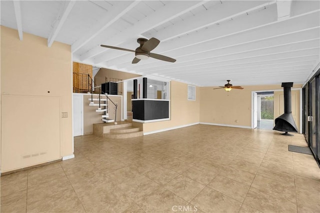 4662 Howard Ave, Los Alamitos, CA 90720 - unfurnished living room featuring a wood stove, a ceiling fan, beam ceiling, stairway, and light tile patterned floors