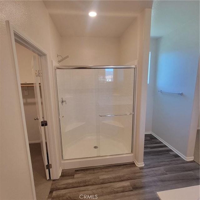 bathroom with a stall shower, wood finished floors, baseboards, and recessed lighting