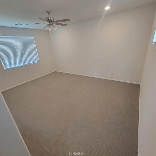 carpeted spare room with ceiling fan and baseboards