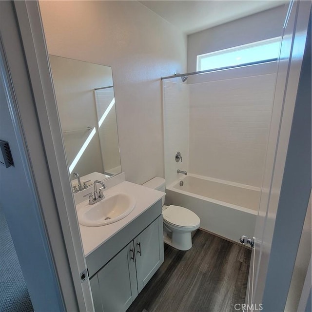 bathroom featuring wood finished floors, vanity, toilet, and shower / washtub combination
