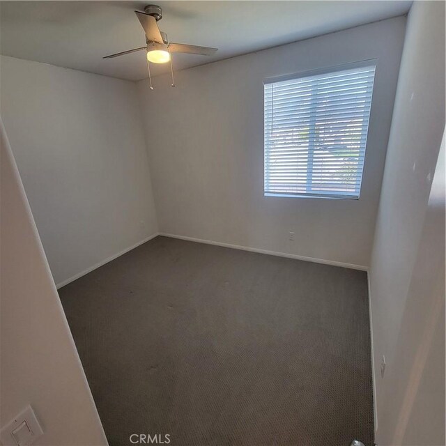 carpeted spare room with a ceiling fan and baseboards