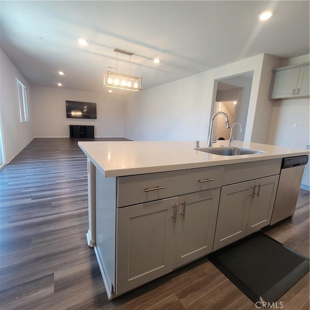 kitchen with a sink, stainless steel dishwasher, open floor plan, light countertops, and dark wood-type flooring