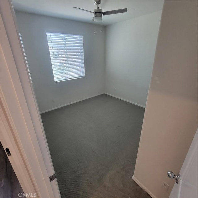 unfurnished room with dark carpet, a ceiling fan, and baseboards