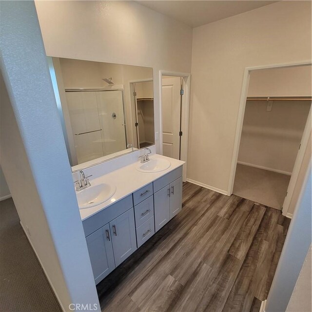 29145 Dune Primrose, Lake Elsinore, CA 92530 - bathroom featuring a spacious closet, a stall shower, double vanity, and wood finished floors