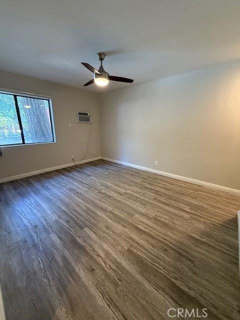 20234 Cantara St Unit 143, Winnetka, CA 91306 - empty room featuring dark wood finished floors, a ceiling fan, and a wall mounted air conditioner