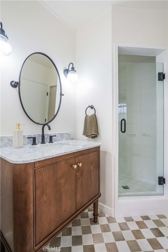 bathroom featuring a shower stall, baseboards, vanity, crown molding, and tile patterned floors