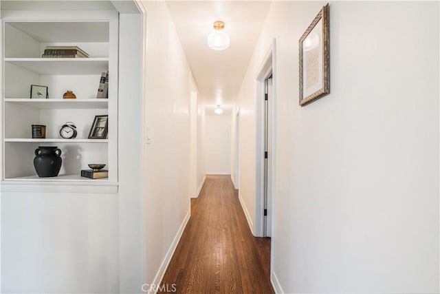 hall with dark wood-style flooring and baseboards