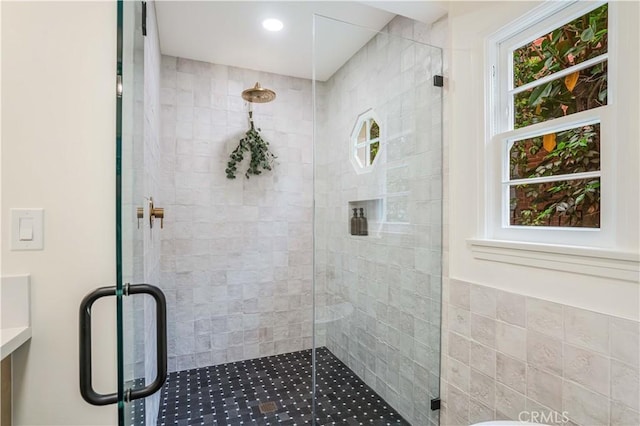 bathroom with a shower stall and tile walls