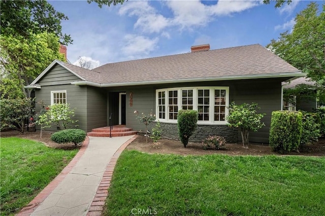 single story home featuring a front lawn, a chimney, and roof with shingles