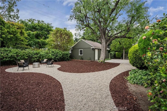 view of yard featuring a patio, an outbuilding, and curved driveway