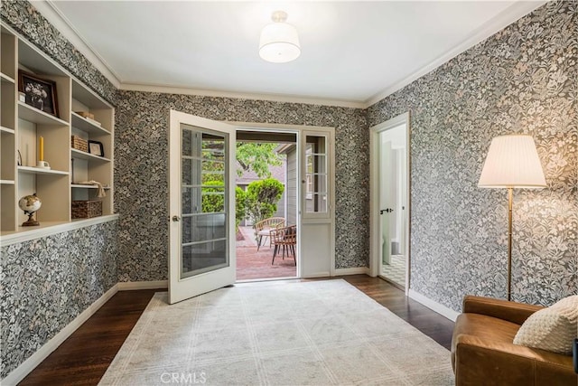 doorway to outside with wallpapered walls, ornamental molding, wood finished floors, and baseboards