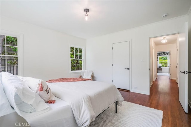 bedroom with dark wood-style floors, multiple windows, and baseboards