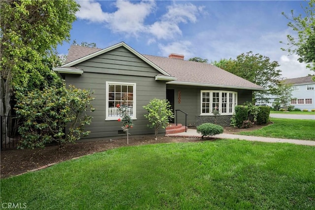 single story home with a front lawn, a chimney, and a shingled roof