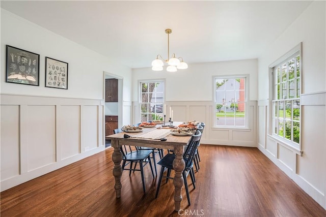dining room featuring a decorative wall, wood finished floors, a chandelier, and a wainscoted wall