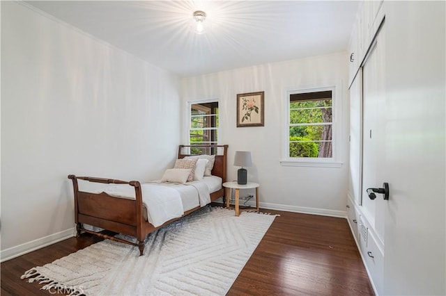 bedroom with dark wood-style flooring, baseboards, and a closet