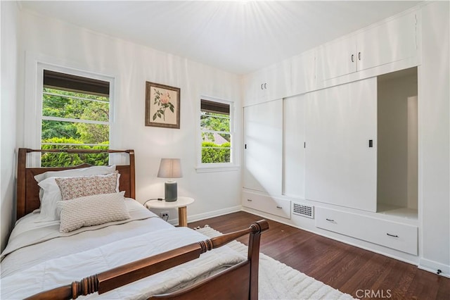bedroom with baseboards, dark wood finished floors, and a closet