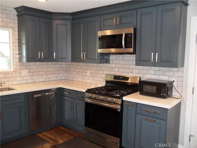 kitchen with stainless steel appliances, light countertops, decorative backsplash, and dark wood-type flooring