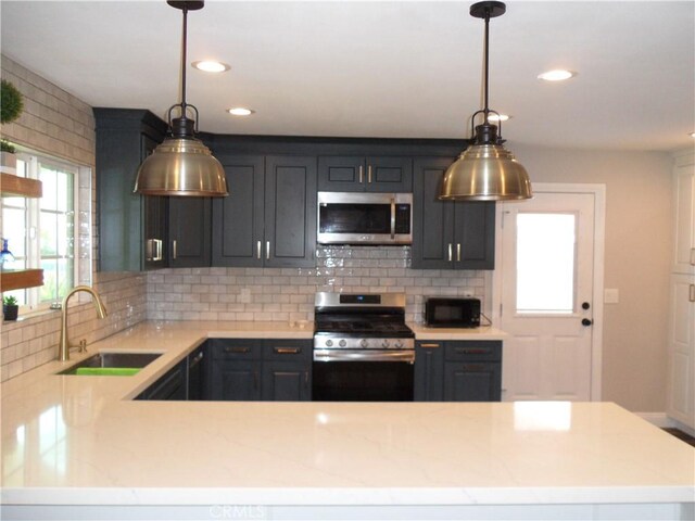 kitchen featuring stainless steel appliances, a sink, tasteful backsplash, recessed lighting, and a peninsula