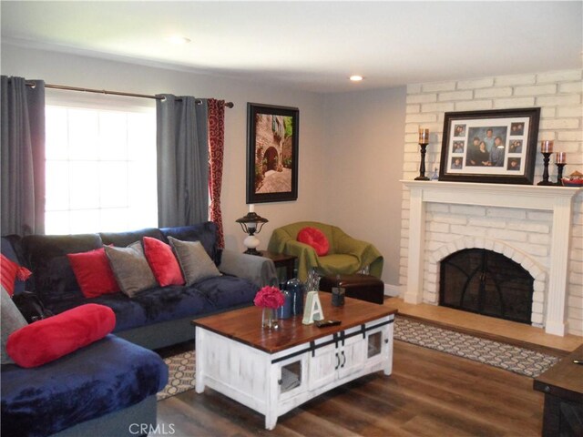 living room with dark wood-type flooring and a brick fireplace