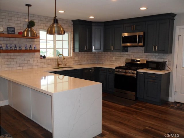 kitchen with stainless steel appliances, a sink, a peninsula, light countertops, and backsplash