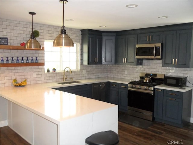 kitchen featuring appliances with stainless steel finishes, a sink, a peninsula, and light countertops