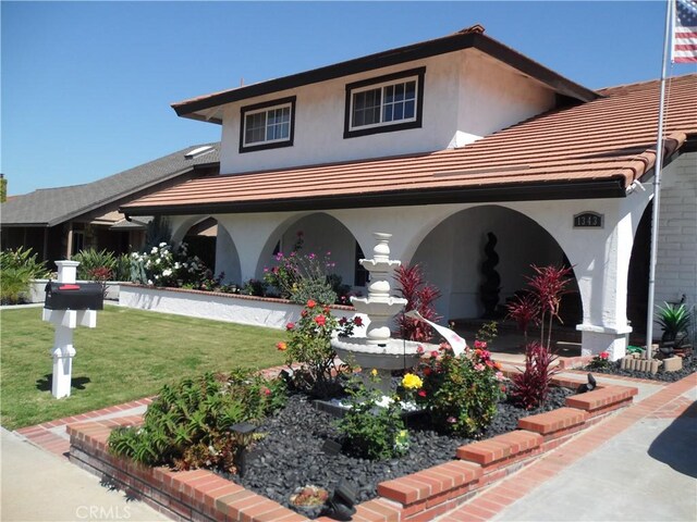 view of front facade with stucco siding, a front lawn, and a tile roof