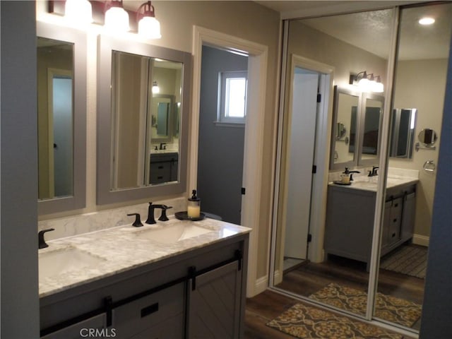 bathroom with wood finished floors, double vanity, and baseboards