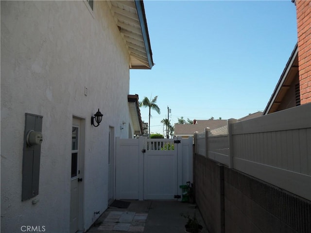 view of property exterior with a gate, stucco siding, and fence