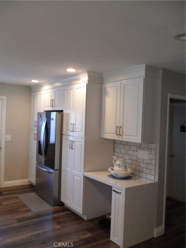 kitchen with fridge with ice dispenser, light countertops, dark wood-style floors, white cabinets, and tasteful backsplash