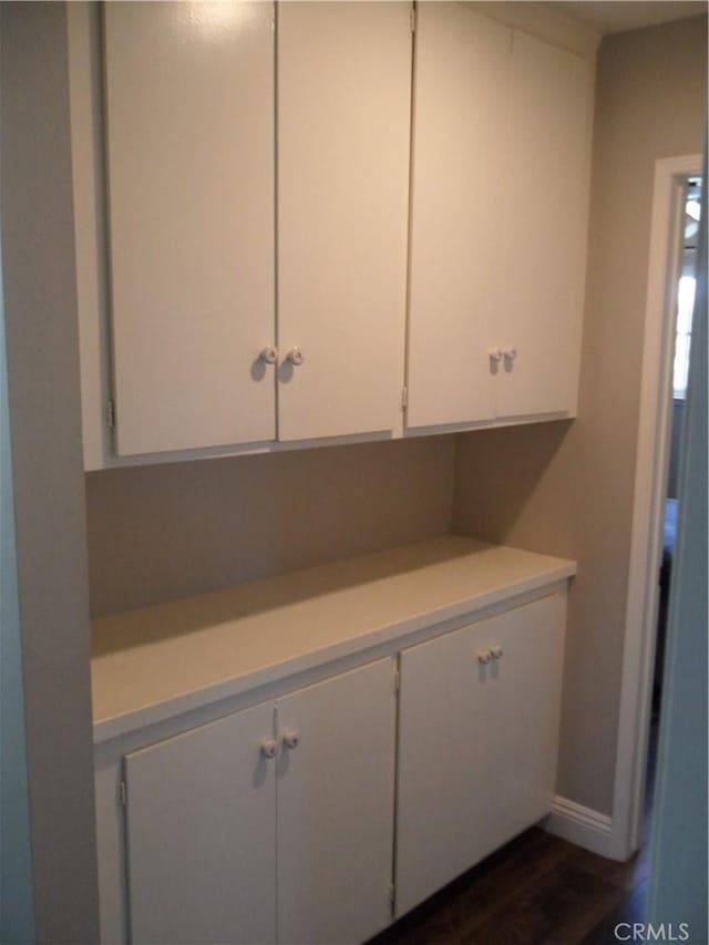 kitchen featuring light countertops, white cabinets, dark wood-style floors, and baseboards